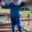 A child crossing the Chain Bridge playground equipment with an adult's support.