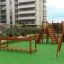 Children's playground with wooden climbing structures, a bridge, and a slide in an urban area, Chain