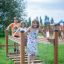 Children playing on Chain Bridge wooden playground equipment.