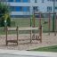 Chain Bridge playground equipment set on sandy ground in a green park.