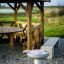 Outdoor grill next to a wooden gazebo with bench and picnic table.