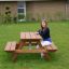 Larchwood Table & Bench for Kids with a girl sitting on the bench in a garden setting