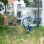Outdoor fitness bike with blue handlebars in a grassy area.