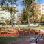 Outdoor fitness equipment in a park with trees and apartment buildings in the background.
