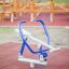 Outdoor fitness equipment resembling rowing machine in a park.