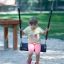 Child sitting on Flat Seat Wooden Swing in playground.