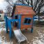 wooden playhouse with a steel slide