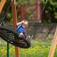 Child swinging on Bird Nest Swing with Tower (BNS 90 cm) playhouse with slide in garden.